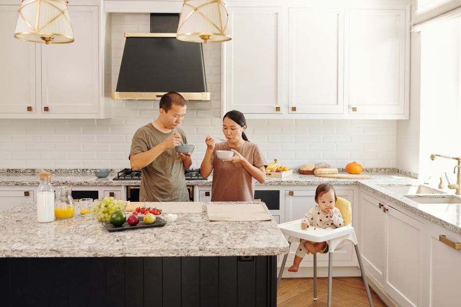 A family enjoys breakfast together in a stylish kitchen with a toddler in a high chair.